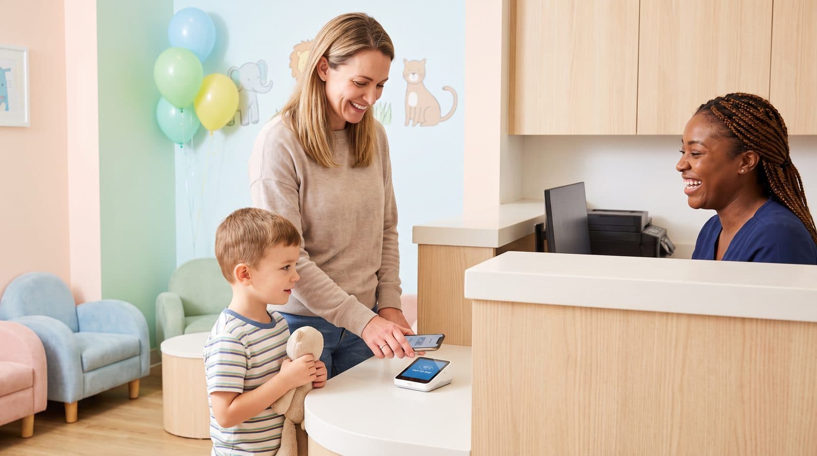 A mother and son pay at a dental front desk